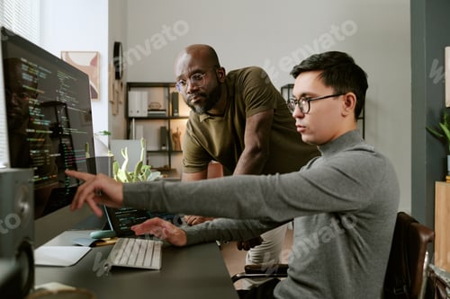 Preview: Young Asian Man Collaborating with Young Black Man While Coding Software