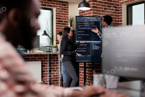 Preview: Software developers standing near vertical screen talking about interface bug