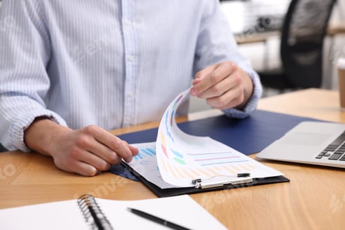 Preview: Man with papers working at wooden desk in office, closeup