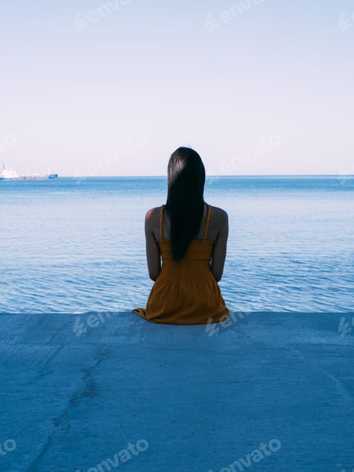Preview: Portrait of young brunette girl with wet hair in yellow dress in the beach. Summer sea background