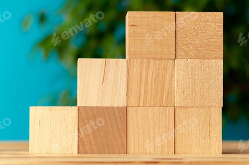 Preview: Wooden blocks on desk against blurred plant background