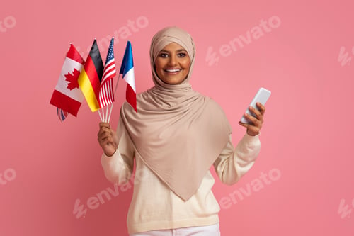 Preview: Online Translator App. Smiling Muslim Woman Holding International Flags And Smartphone