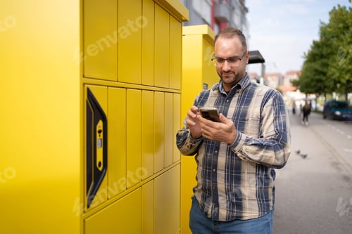 Preview: Man checks smartphone next to bright yellow lockers