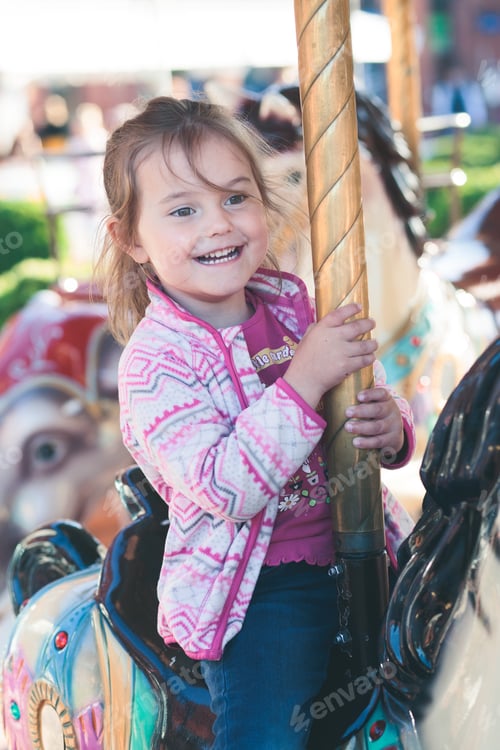 Preview: Funfair. Little girl riding a horse on roundabout carousel at funfair. Fun and happy play