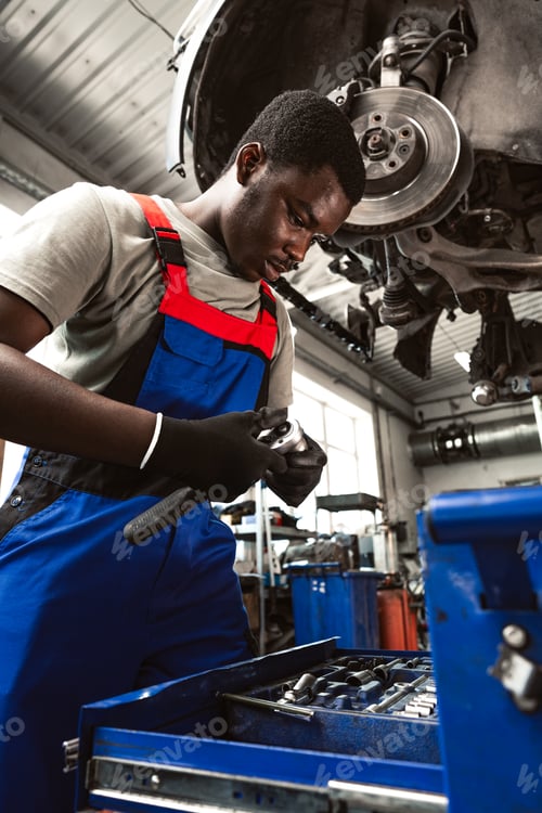 Preview: Young african mechanic in uniform working in a car service shop