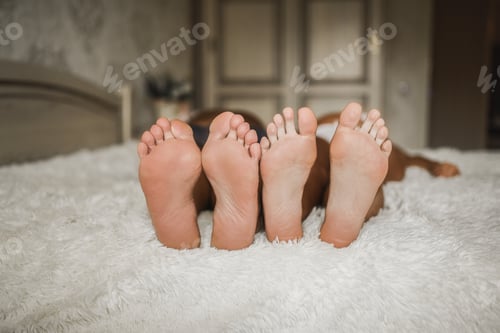Preview: Adult man and a woman with bare feet are lying on the bed