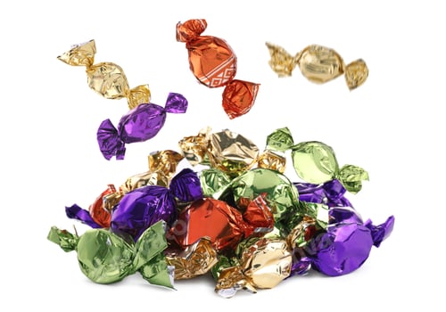 Preview: Candies in bright wrappers falling onto heap against white background