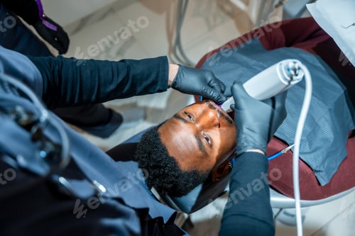 Preview: Dentist performing teeth whitening procedure on patient in modern clinic