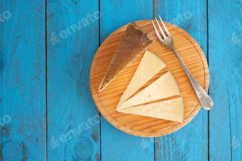 Preview: Delicious cheese slices served on a wooden board with a waffle cone on a bright blue table