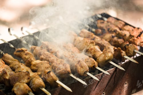 Preview: Marinated shashlik preparing on a barbecue grill over charcoal. Shashlik or Shish kebab popular in
