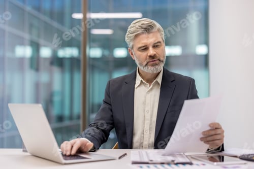 Preview: Professional businessman analyzing documents in modern office workspace