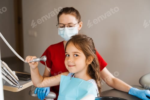 Preview: Cheerful girl holding dental tools and smiling during friendly dentist consultation