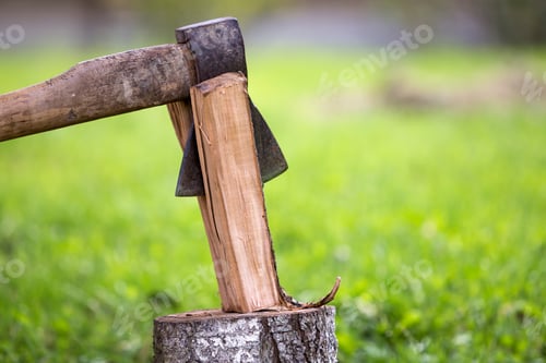 Preview: Close-up of old sharp dirty weathered iron ax cutting through chunk of firewood