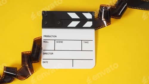 Preview: Small white clapper board and film roll on yellow background. It use in movie and video production.