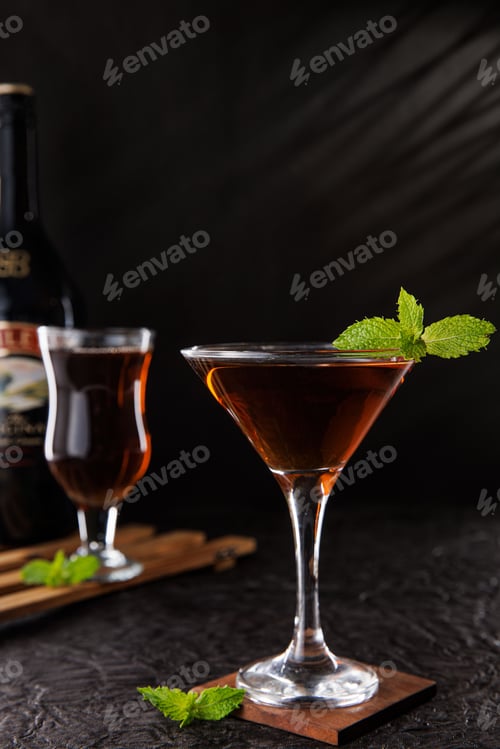 Preview: Glass of cocktail garnished with mint leaves in a dark room