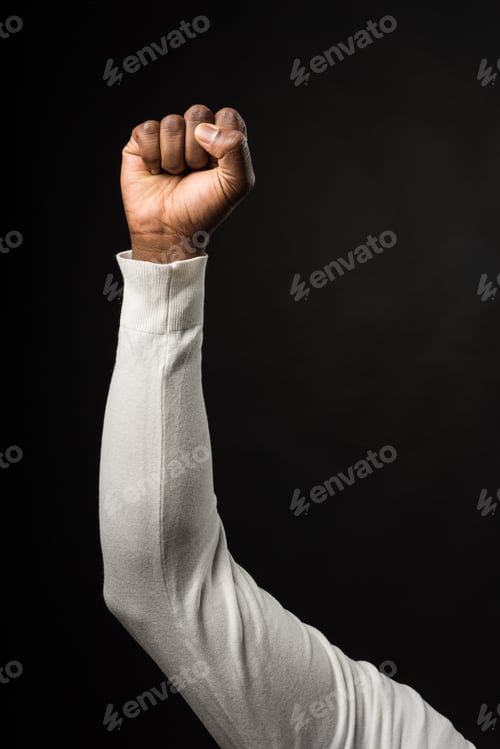 Preview: Raised fist of a black man, on black background.