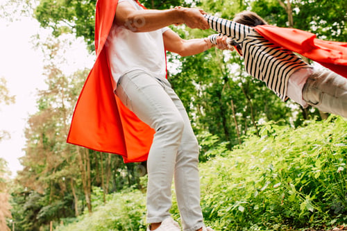 Preview: cropped view of father spinning little boy in red cloak