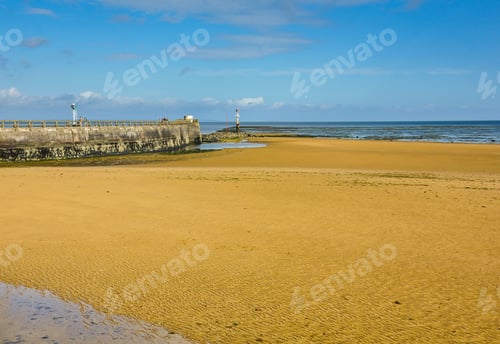 Preview: Historic sandy shore with a broken pier in Grandcamp-Maisy, Normandy, France
