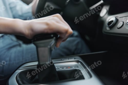 Preview: Car interior with unique central steering wheel design and driver shifting gears, hand on the gear