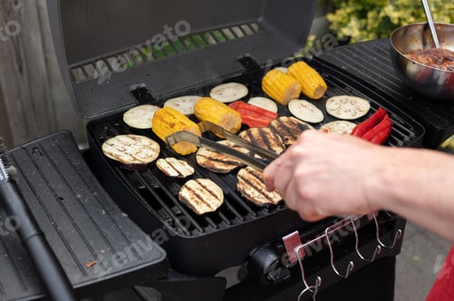 Preview: Grilling vegetables and corn on barbecue grill with male hand tongs