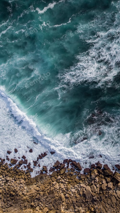 Preview: Vertical aerial shot of waves crashing to the coastline in portugal