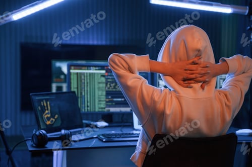 Preview: Young professional female hacker is indoors by computer with lot of information on displays