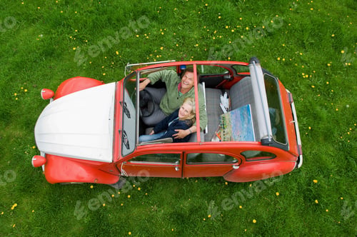 Preview: View from above of two people, a couple in a car with the roof open.