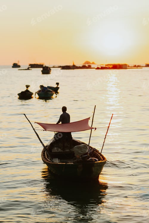 Preview: Man driving his boat on the South China Sea in Vietnam at sunset while other boats are in background