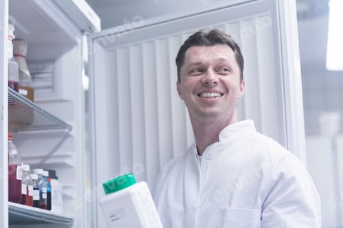 Preview: Scientist holding bottle of chemical removed from cabinet