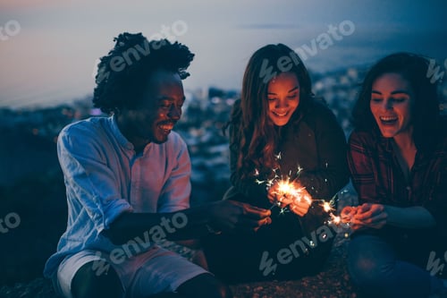 Preview: Millennial group of friends lighting sparklers at night