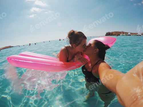 Preview: Lgbt lesbian gay couple kissing in ocean on vacation holiday in summer