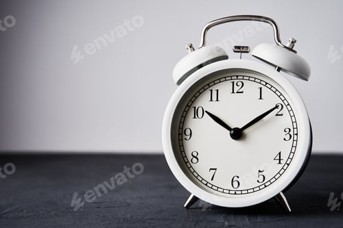 Preview: White vintage alarm clock on a black background with copy space