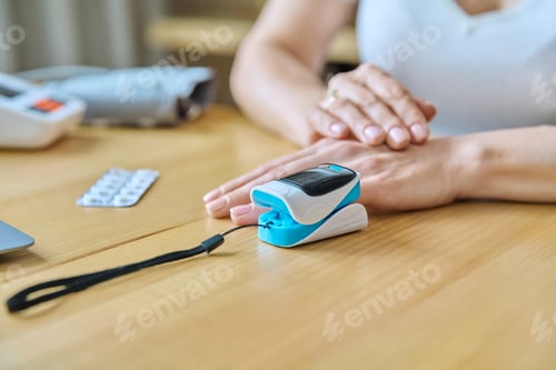 Preview: Middle-aged woman measuring level of oxygen in blood using pulse oximeter