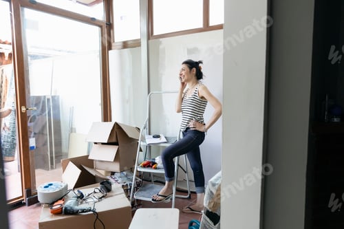 Preview: Woman laughing during a moving day break amidst boxes and belongings