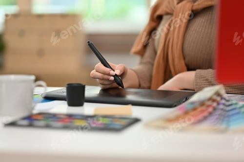 Preview: Young creative woman using graphic tablet and working with color swatch samples at modern workplace.