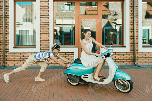 Preview: side view of man helping excited woman riding retro scooter