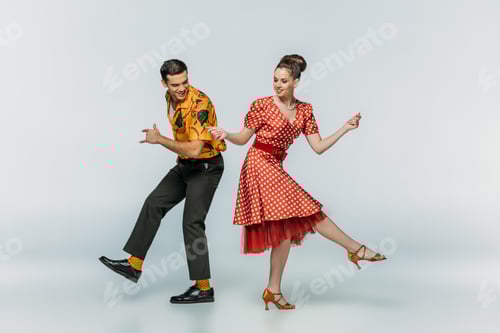 Preview: young dancers holding hands while dancing boogie-woogie on grey background