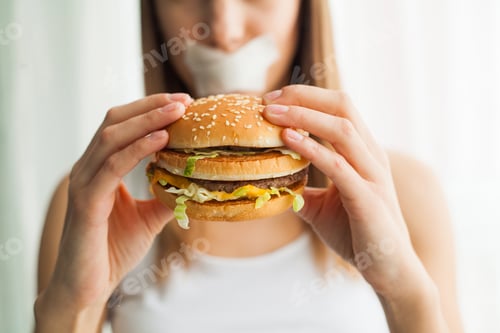 Preview: Young woman with duct tape over her mouth, preventing her to eat junk food
