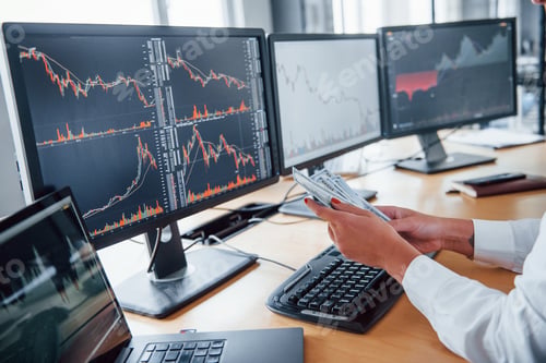 Preview: Close up view of woman's hands that holds money near the monitors with graphs
