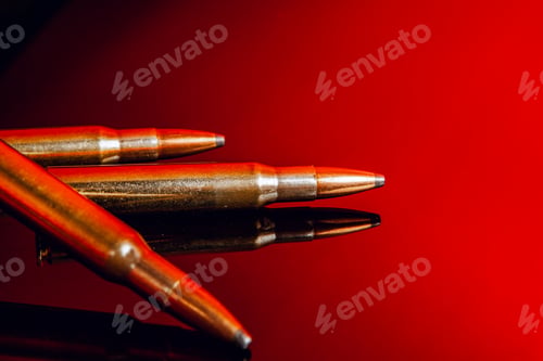 Preview: Rifle bullets or cartridges on black shiny background with red reflection