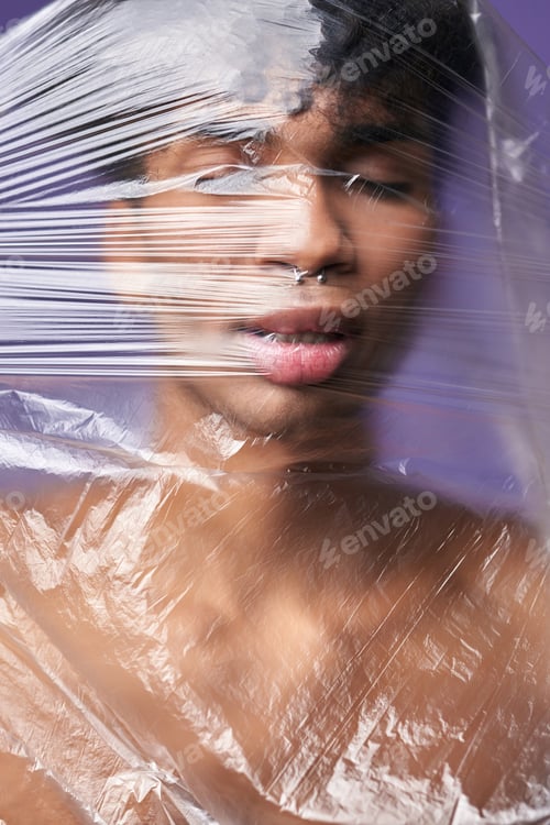 Preview: Portrait of young transgender man with plastic bag on head. Trans gender model stop breathe