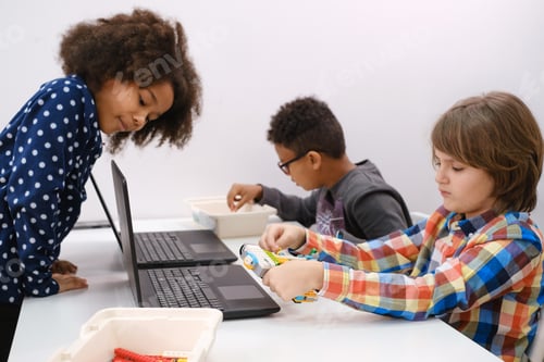 Preview: Multi ethnic children at technology lesson coding robot on tablet