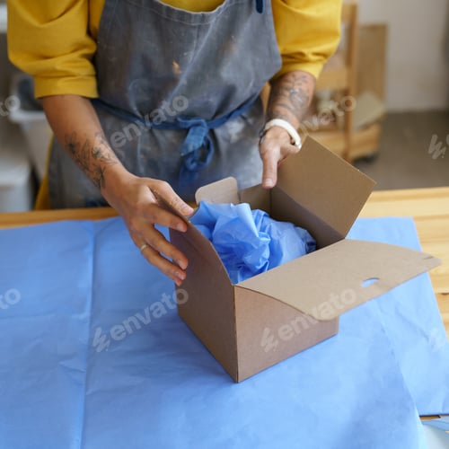 Preview: Deliver parcel: girl potter artist in apron packing ceramics in box with paper for safe shipping