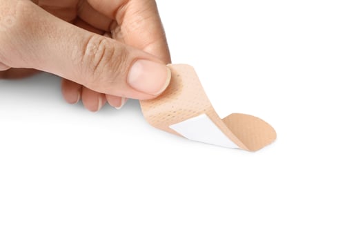 Preview: Woman putting sticking plaster on white background. First aid item