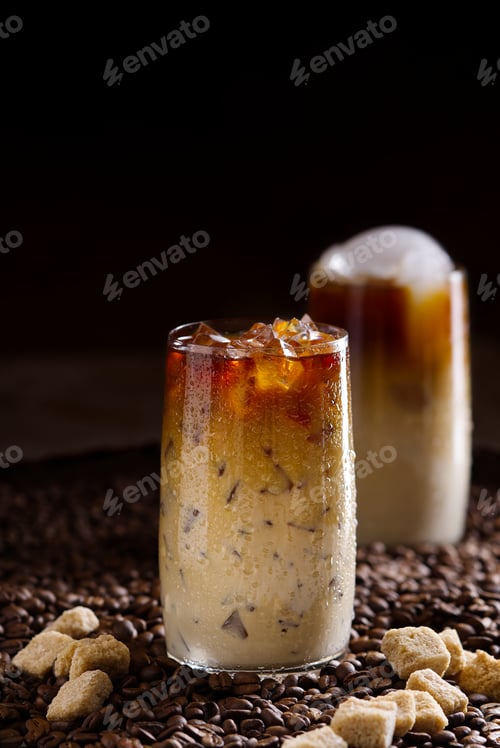 Preview: Iced coffee. Tasty ice coffee with milk, cold drink in glass with ice on dark coffee background.