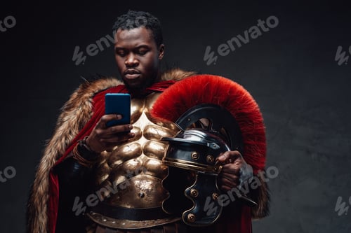 Preview: Black man in roman soldier costume using smartphone
