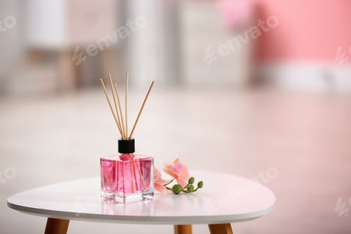 Preview: Aromatic reed air freshener and flowers on table against blurred background