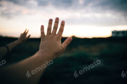 Preview: Couple hands on background of beautiful sandy cliff and sunset sky