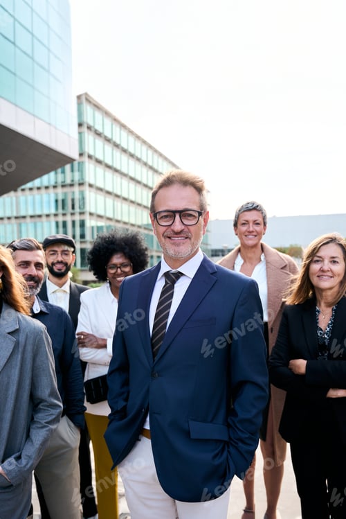 Preview: Cheerful smiling team of diverse business people in formal suit looking confident at camera