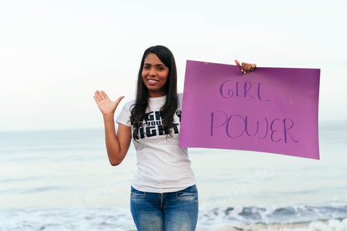 Preview: Latin american woman showing girl power sign at beach